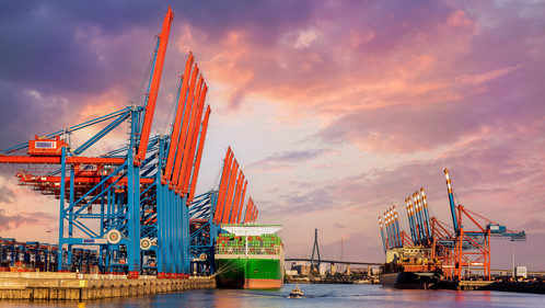 Strategien gegen den Sanierungsstau - Wasserstraße Scenic front giant cargo container ship loading Hamburg city port harbour seaport cranes warm dramatic sky evening sunset light. Global commercial trade freight charter shipping logistics background.