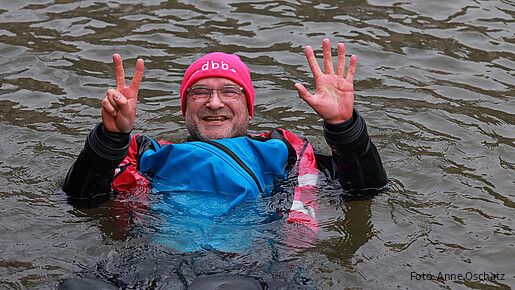 Ein Mann in Neoprenanzug badet in einem Fluss