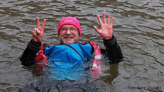 Ein Mann in Neoprenanzug badet in einem Fluss