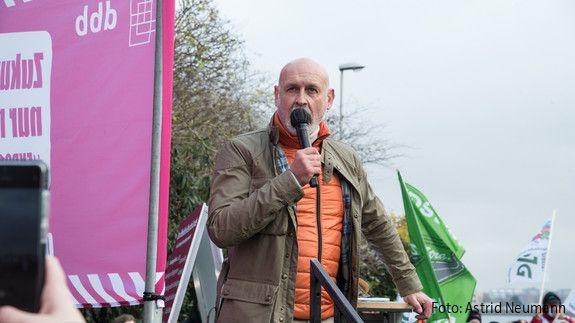 Einkommensrunde Aktion Kiel Ein Mann steht vor einer Gruppe Menschen und spricht in ein Mikrofon