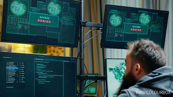 Cybersicherheit Ein Mann sitzt vor mehreren Computer-Monitoren, auf denen "Zugriff verweigert" zu lesen ist.