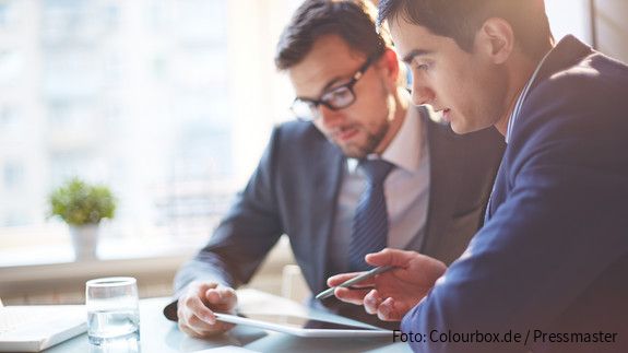 Digitalisierung Zwei Männer im Büro sehen gemeinsam auf Tablet und besprechen sich