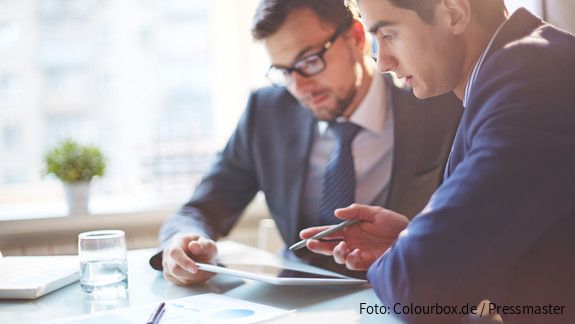 Digitalisierung Zwei Männer im Büro sehen gemeinsam auf Tablet und besprechen sich