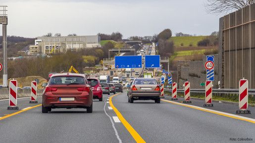 Zu sehen sind Autos auf einer Autobahn, rechts und links am Fahrbahnrand stehen Baustellen-Barken.