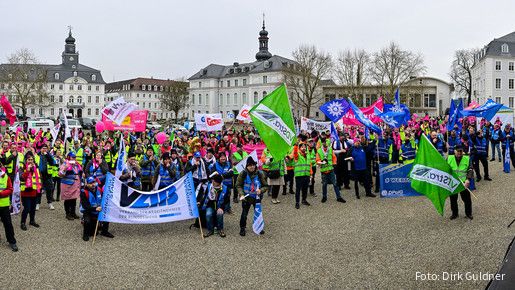 Eine Menschenmenge mit bunten Warnwesten und Fahnen auf dem Schlossplatz in Saarbrücken