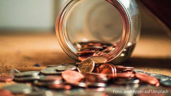 Geldmünzen fallen aus einem Glas