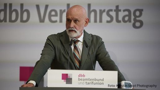 Ein Mann in Anzug steht hinter einem Rednerpult und spricht in ein Mikrofon