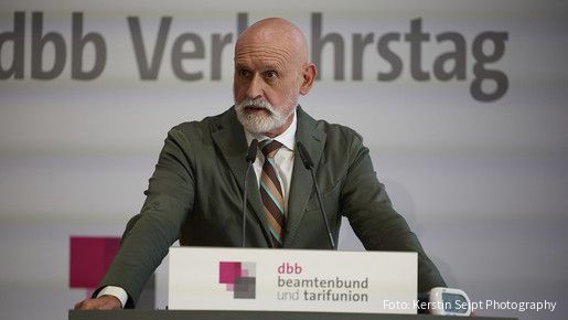 Ein Mann in Anzug steht hinter einem Rednerpult und spricht in ein Mikrofon