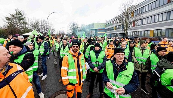 Menschen in grünen Warnwesten demonstrieren auf einem öffentlichen Platz.