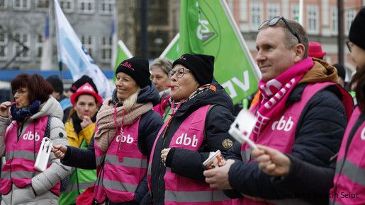 Eine Gruppe Menschen in pinken Warnwesten macht Lärm mit Pfeifen und Rätschen