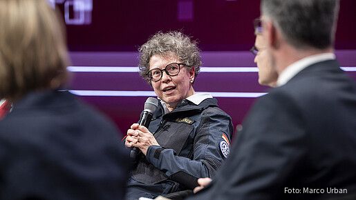Eine Frau sitzt auf der Bühne und diskutiert mit anderen Teilnehmern. Es handelt sich um Sabine Lackner, THW-Präsidentin