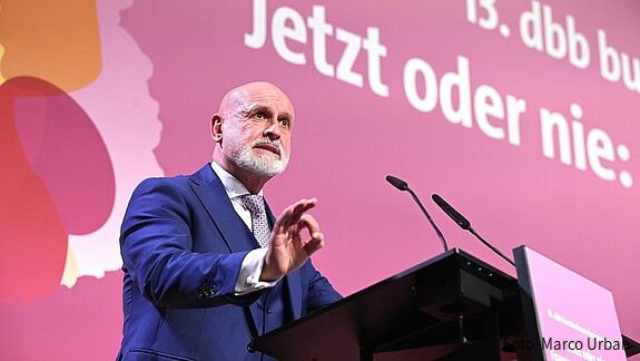 Ein Mann steht hinter einem Rednerpult und spricht in das Mikrofon