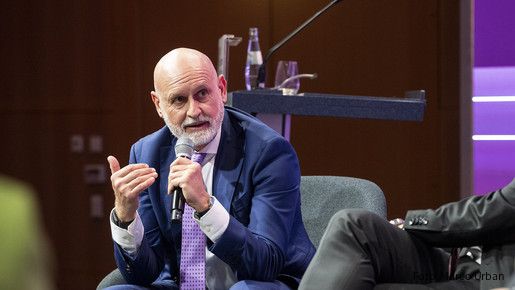Ein Mann hält ein Mikrofon in der Hand und Diskutiert mit anderen Menschen