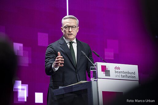 Ein Mann steht auf einer Bühne hinter einem Rednerpult und spricht in ein Mikrofon. Es handelt sich um Karsten Wildberger, Bundesminister für Digitales und Staatsmodernisierung