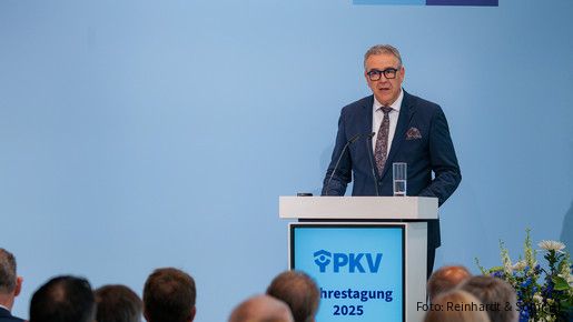 Ein Mann in Anzug steht hinter einem Rednerpult und spricht in ein Mikrofon