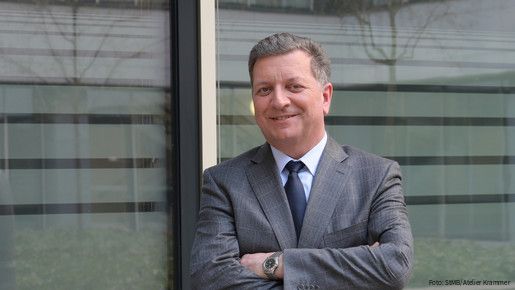 Foto von einem Mann im Anzug vor einer Glaswand