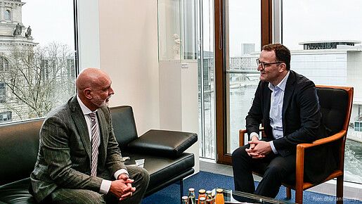 Zwei Männer in Anzügen sitzen in einem Büro und diskutieren miteinander