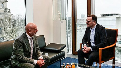 Zwei Männer in Anzügen sitzen in einem Büro und diskutieren miteinander