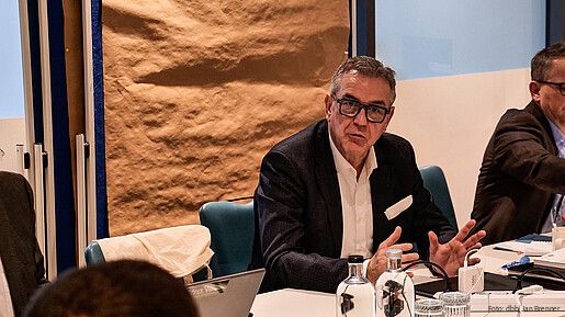 Ein Mann sitzt an einem Tisch in einem Seminarraum und diskutiert.