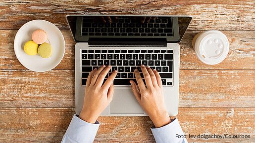 Das Foto zeigt eine Laptoptastatur, man sieht noch den Bildschirm und Finger, die auf der Tastatur tippen.